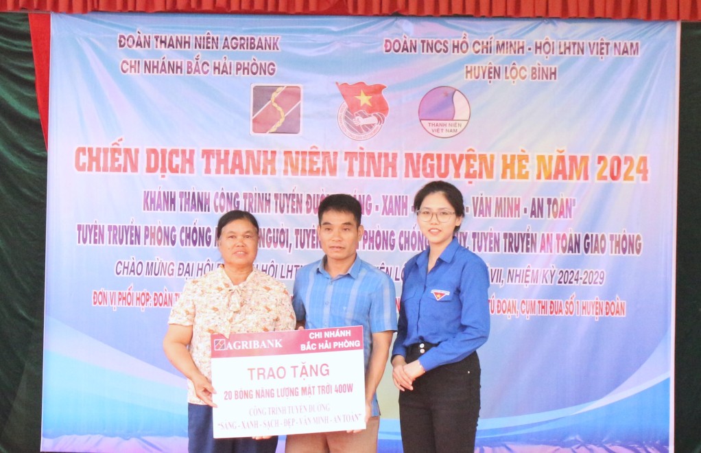 Đại diện Đoàn Thanh niên Ngân hàng Nông nghiệp và Phát triển nông thôn Việt Nam (Agribank) chi nhánh Bắc Hải Phòng trao biểu trưng hỗ trợ bóng đèn cho công trình “Tuyến đường sáng- xanh - sạch - đẹp - văn minh - an toàn” tại xã Tú Đoạn