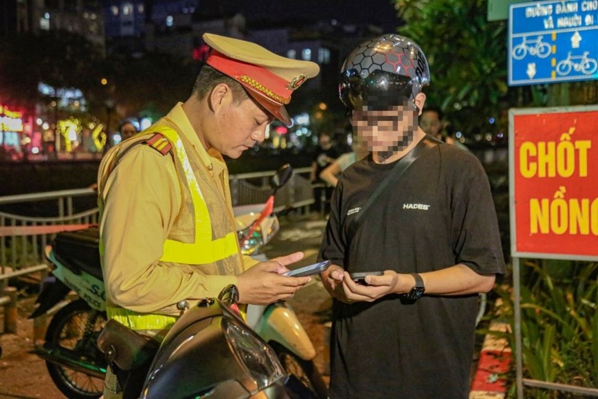 Cảnh sát giao thông tại Hà Nội kiểm tra giấy tờ của người tham gia giao thông qua ứng dụng VneID. 