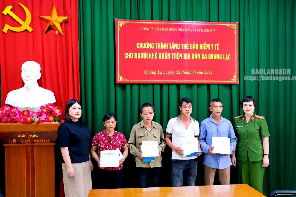 Đại diện lãnh đạo công ty và lãnh đạo Công an thành phố trao thẻ bảo hiểm y tế và quà cho người dân có hoàn cảnh khó khăn trên địa bàn xã Quảng Lạc