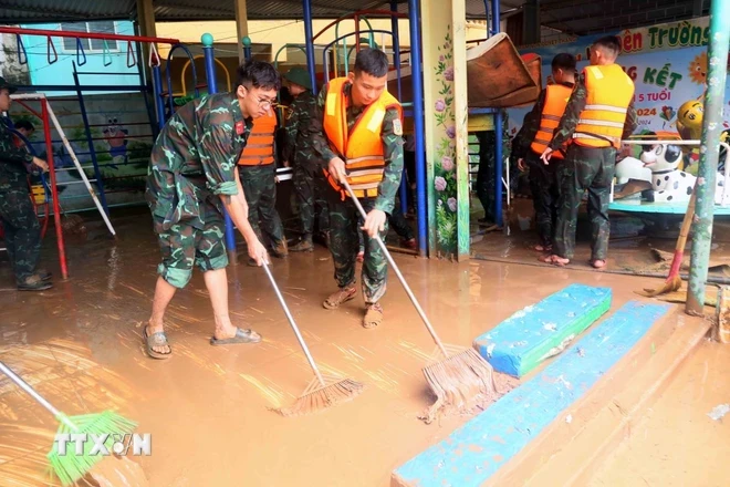 Bộ đội tham gia giúp dân dọn vệ sinh sau khi nước rút. (Ảnh: Quang Quyết/TTXVN)