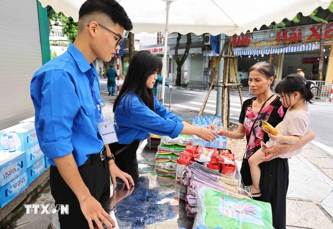 Các tình nguyện viên Thủ đô cung cấp nước uống, đồ ăn nhẹ, quạt giấy cho người dân. (Ảnh: Minh Đức/TTXVN)