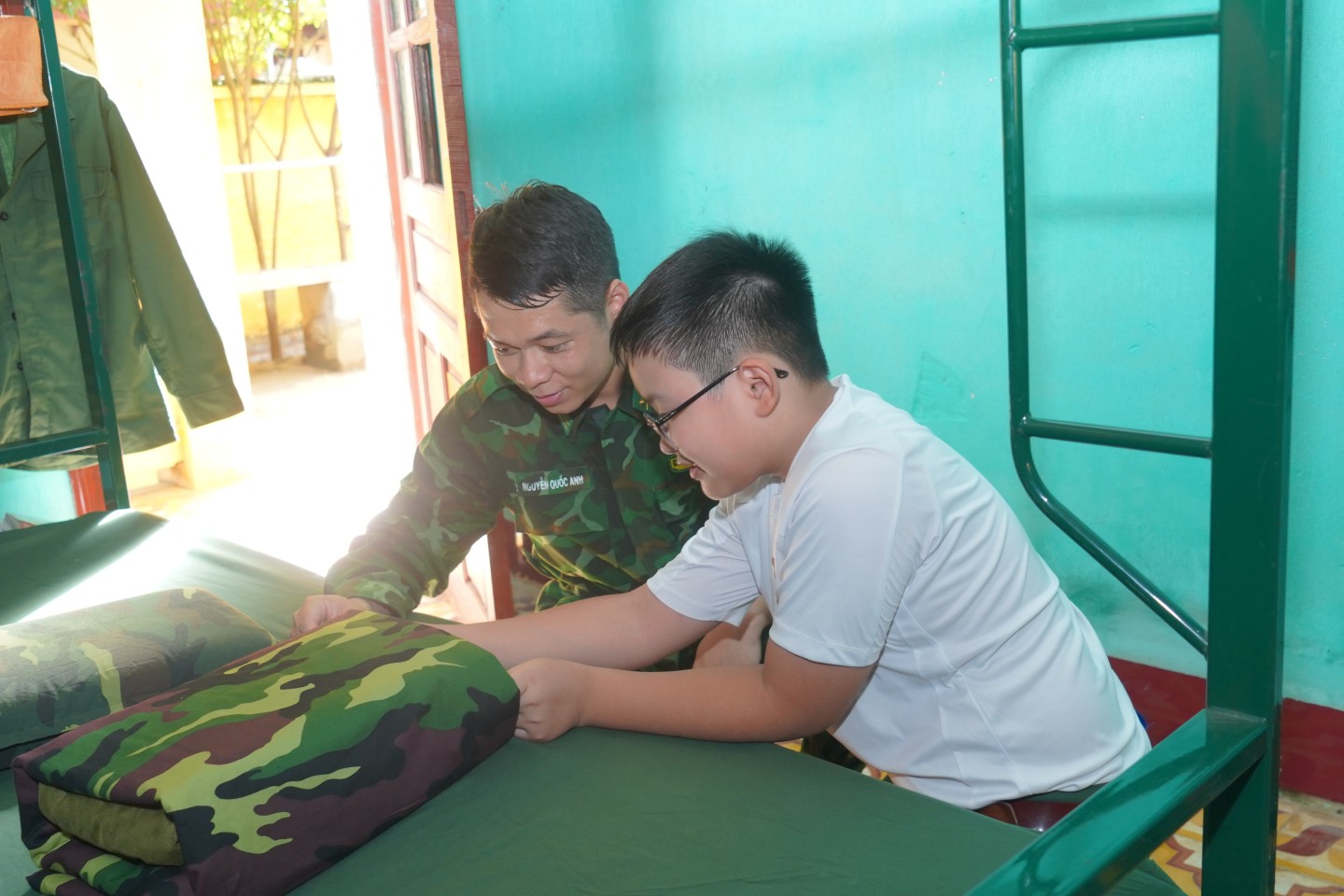 Các em được cán bộ, chiến sĩ của Tiểu đoàn hướng dẫn thực hành gấp chăn màn, sắp xếp nội vụ vệ sinh. Mỗi em đều rất tập trung lắng nghe hướng dẫn rồi cẩn thận vuốt kĩ từng nếp gấp, sao cho tấm chăn, tấm màn thật vuông vức, góc cạnh. Em Hoàng Triệu Đức Mạnh (sinh năm 2008, thị trấn Cao Lộc, huyện Cao Lộc) chia sẻ: 