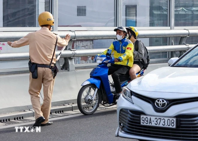 Lực lượng CSGT dừng xe kiểm tra và xử lý các trường hợp người điều khiển xe máy đi vào đường Vành đai 2 trên cao. (Ảnh: Phạm Kiên/TTXVN)