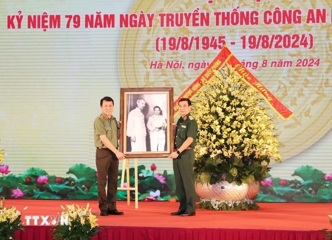 Đại tướng, Bộ trưởng Quốc phòng Phan Văn Giang, thay mặt Quân ủy Trung ương, Bộ Quốc phòng trao tặng bức ảnh Bác Hồ cho Thượng tướng, Bộ trưởng Công an Lương Tam Quang, thay mặt Đảng ủy Công an Trung ương, Bộ Công an. (Ảnh: Trí Dũng/TTXVN)