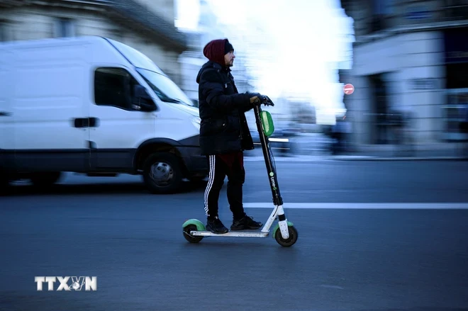 Một người đàn ông lái xe điện e-scooter tại Paris, Pháp. (Ảnh: AFP/TTXVN)