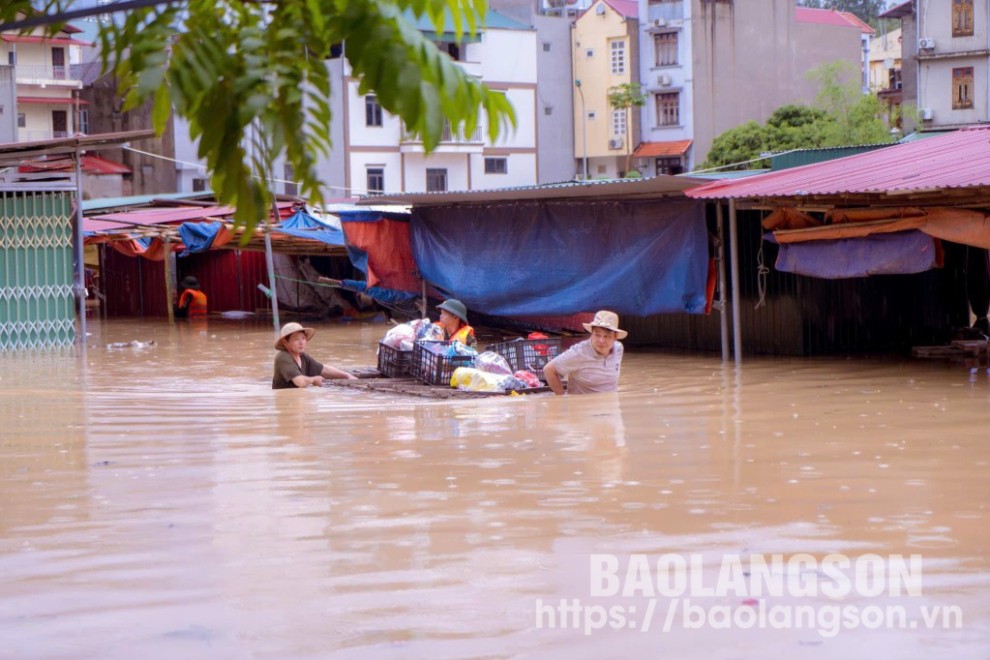 Lực lượng chức năng hỗ trợ người dân di chuyển hàng hóa bị ngập lụt tại chợ thị trấn Na Sầm, huyện Văn lãng