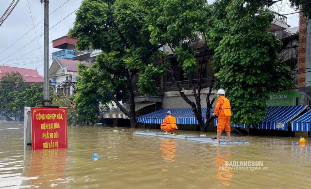 Cán bộ Điện lực Tràng Định đi bè vào khu vực ngập lụt để xử lý sự cố về điện