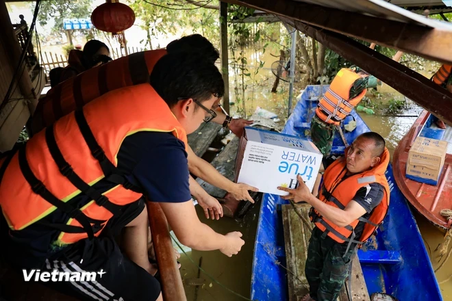 Trao tặng nước tinh khiết cho bà con vùng lũ. (Ảnh: Hoài Nam/Vietnam+)