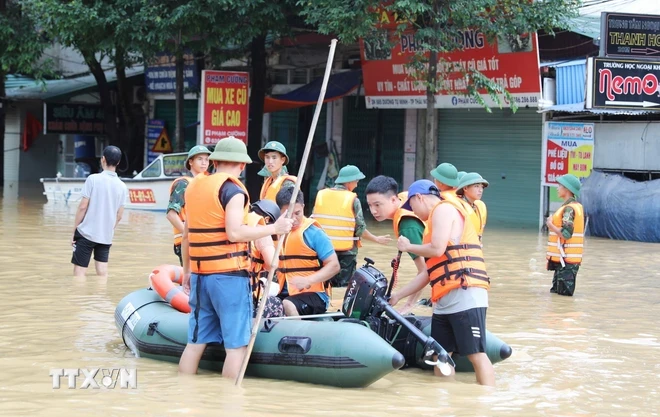 Các lực lượng chức năng sử dụng mọi phương tiện để vận chuyển nhu yếu phẩm đến với người dân bị ngập sâu tại phường Quang Vinh, thành phố Thái Nguyên. (Ảnh: Hoàng Nguyên/TTXVN)