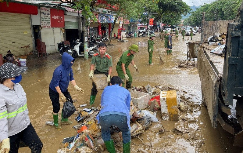 Người dân và cán bộ Công an dọn dẹp đường phố sau mưa lũ.