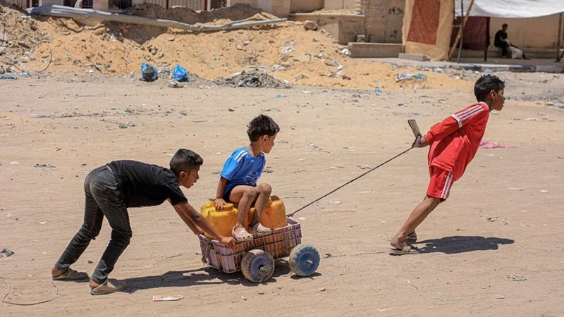 Các em nhỏ vận chuyển nước tại Khan Younis, Dải Gaza, ngày 31/5/2024. (Ảnh: THX/TTXVN)