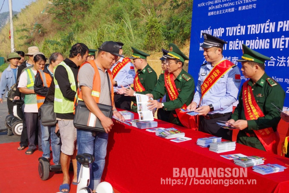 Lực lượng chức năng hai bên phát tờ rơi tuyên truyền pháp luật cho người dân qua lại cửa khẩu hai bên