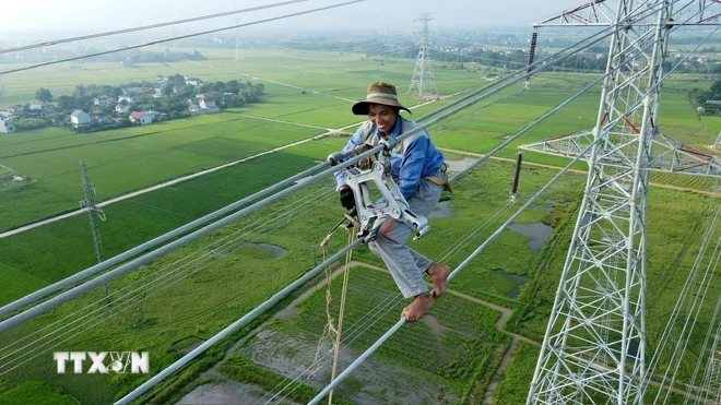 Công nhân kỹ thuật đu dây lắp khung định vị tại Dự án đường dây 500kV mạch 3. (Ảnh: Việt Hoàng/TTXVN)