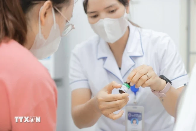 Nhân viên y tế thông tin về vaccine phòng chuẩn bị tiêm cho trẻ. (Ảnh: Minh Quyết/TTXVN)