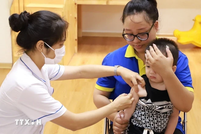 Nhân viên y tế tiêm vaccine phòng bệnh sởi cho trẻ tại điểm tiêm phường Chương Dương, quận Hoàn Kiếm. (Ảnh: Vân Chi/TTXVN phát)