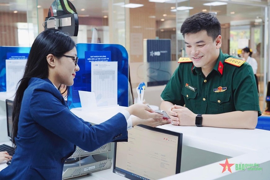 Nhân viên MB tư vấn khách hàng các dịch vụ ngân hàng số trên ứng dụng MBBank cài đặt trên điện thoại. Ảnh: THU HIỀN