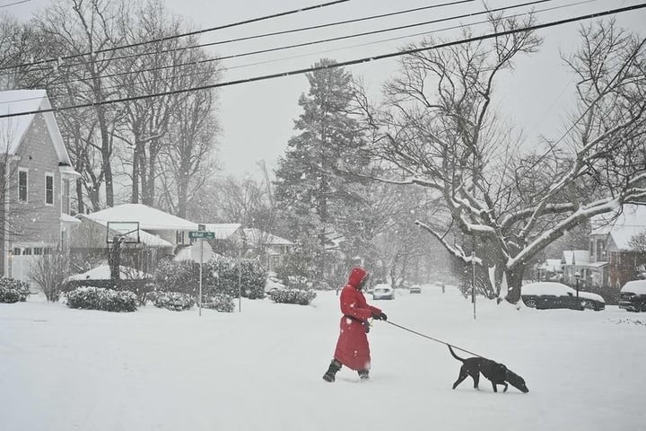 Người đi bộ băng qua con đường phủ tuyết trắng xóa do bão mùa đông gây ra. (Ảnh: Getty)