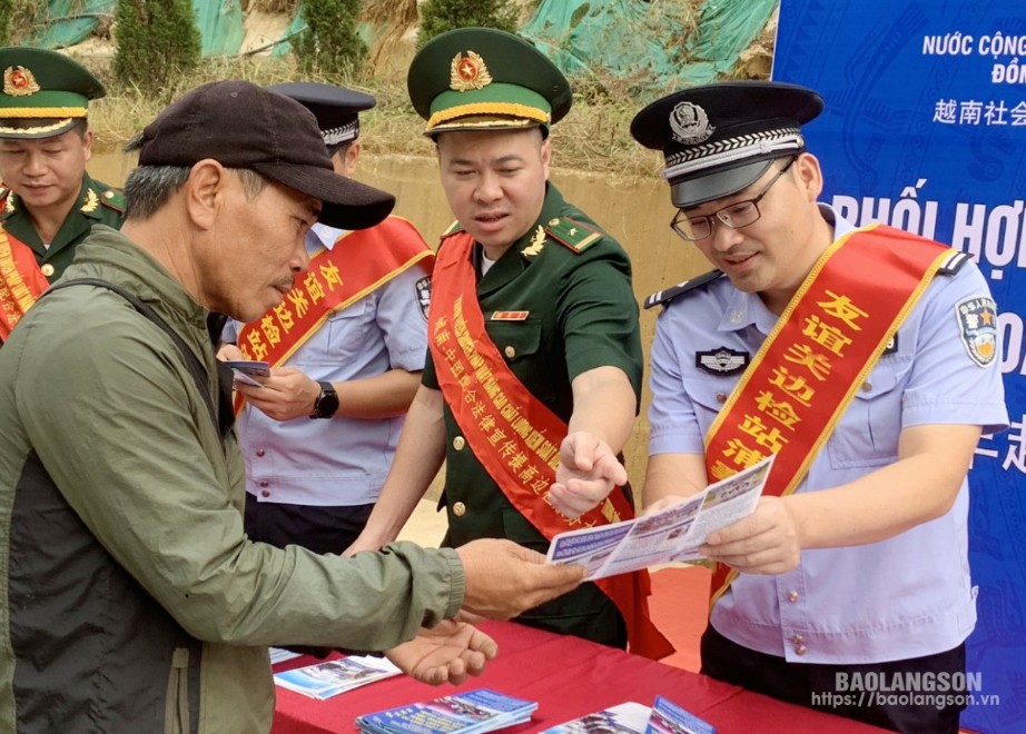 Cán bộ Trạm Biên phòng Tân Thanh (Việt Nam) và lực lượng chức năng phía Trung Quốc phối hợp tuyên truyền, phát tờ rơi về pháp luật cho người dân qua lại cửa khâu hai bên