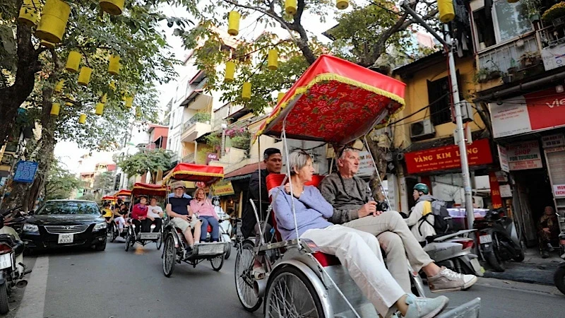 Du khách nước ngoài sử dụng xích-lô thưởng ngoạn nét đẹp cổ kính của Phố cổ Hà Nội. (Ảnh: TTXVN)