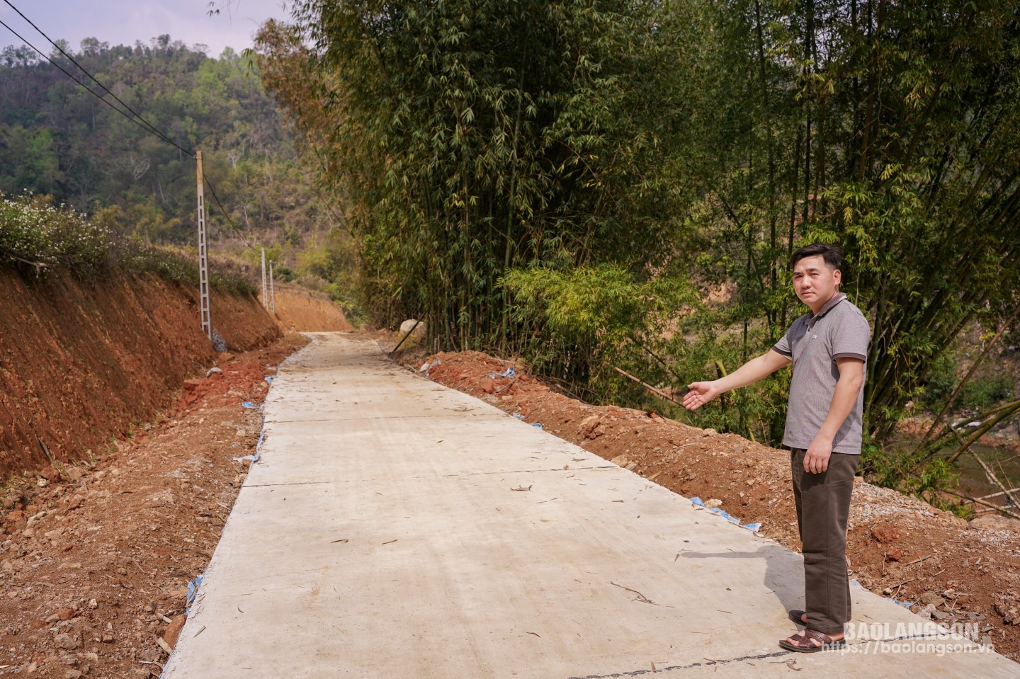 Anh Hữu bên con đường bê tông kiên cố, được xây dựng trên diện tích đất của gia đình tự nguyện hiến tặng