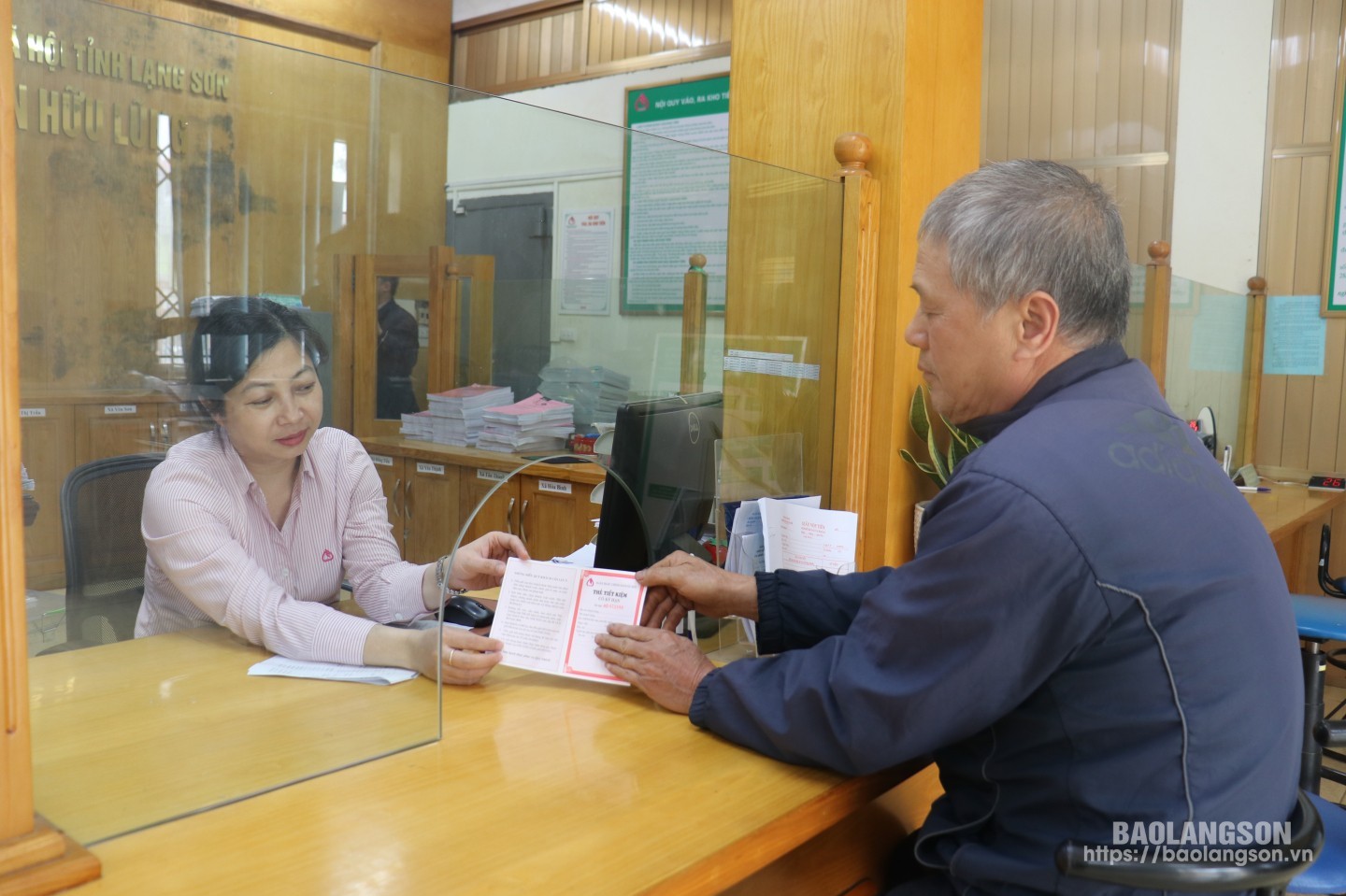 Cán bộ Phòng Giao dịch NHCSXH huyện Hữu Lũng trao sổ tiết kiệm cho người dân tham gia gửi tiết kiệm tại ngân hàng