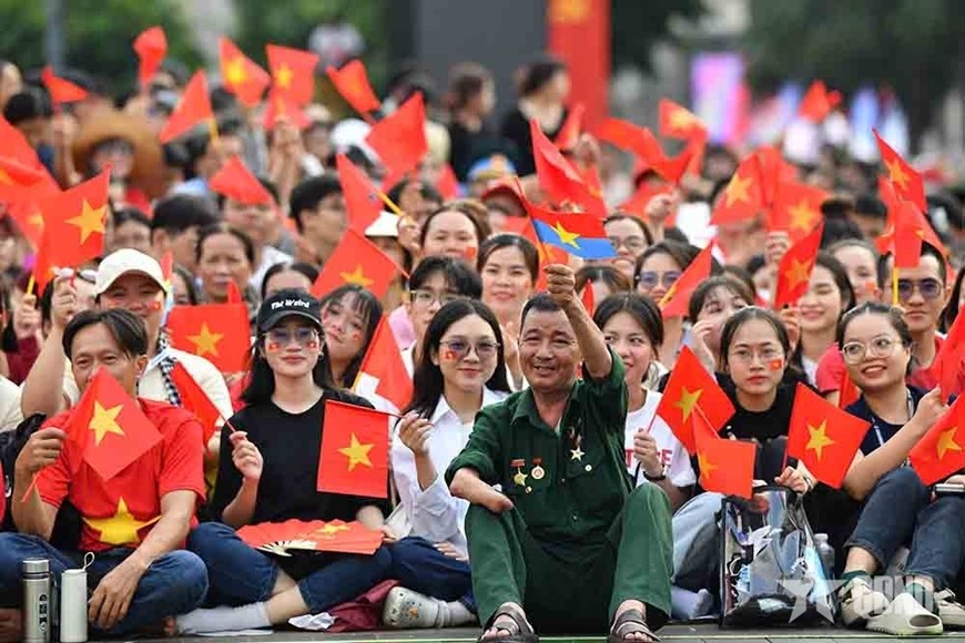 Một cựu chiến binh cùng đông đảo bạn trẻ mang theo cờ đỏ sao vàng đón mừng Lễ kỷ niệm 50 năm Ngày giải phóng miền Nam, thống nhất đất nước. Ảnh: qdnd.vn