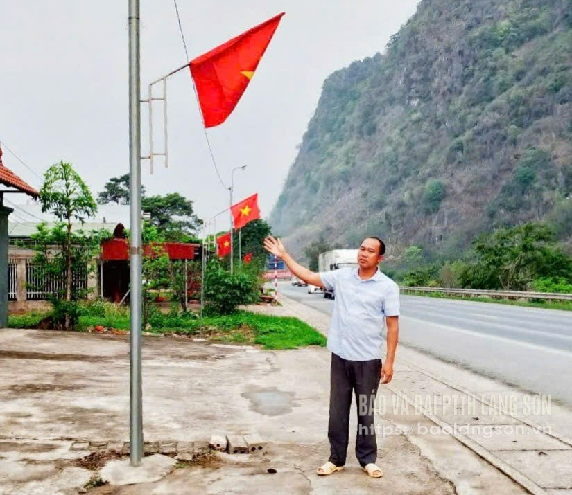 Ông Bùi Hồng Quyết bên đường cờ và công trình thắp sáng đường thôn