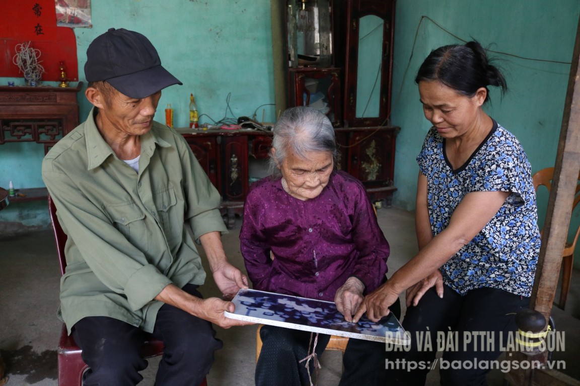 Bà Triệu Thị Lạng xem lại tấm ảnh chụp cùng Bác Hồ năm 1957 tại Trường Sư phạm miền núi Trung ương