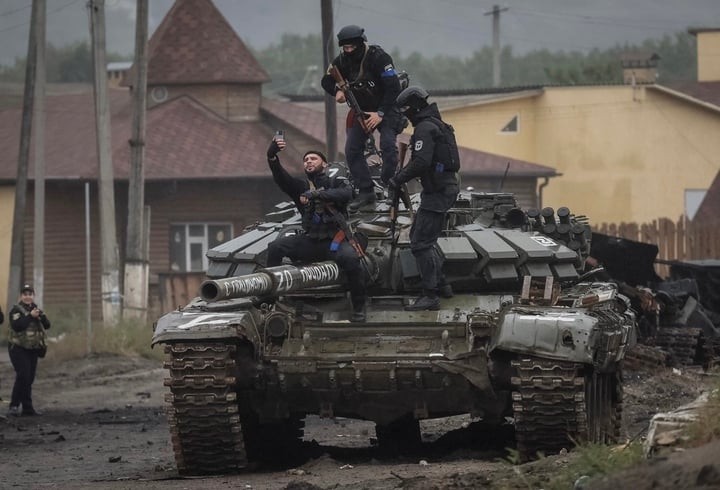 Cảnh sát Ukraine chụp ảnh trên chiếc xe tăng của Nga. (Ảnh: Reuters)