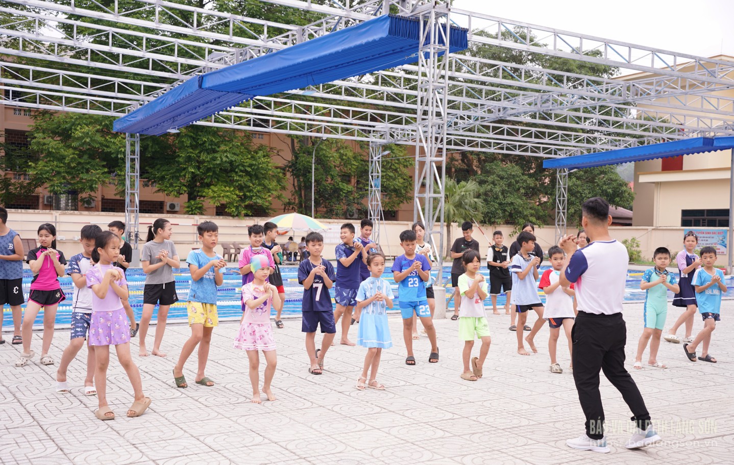Huấn luyện viên hướng dẫn kỹ năng bơi lội cho các em học sinh