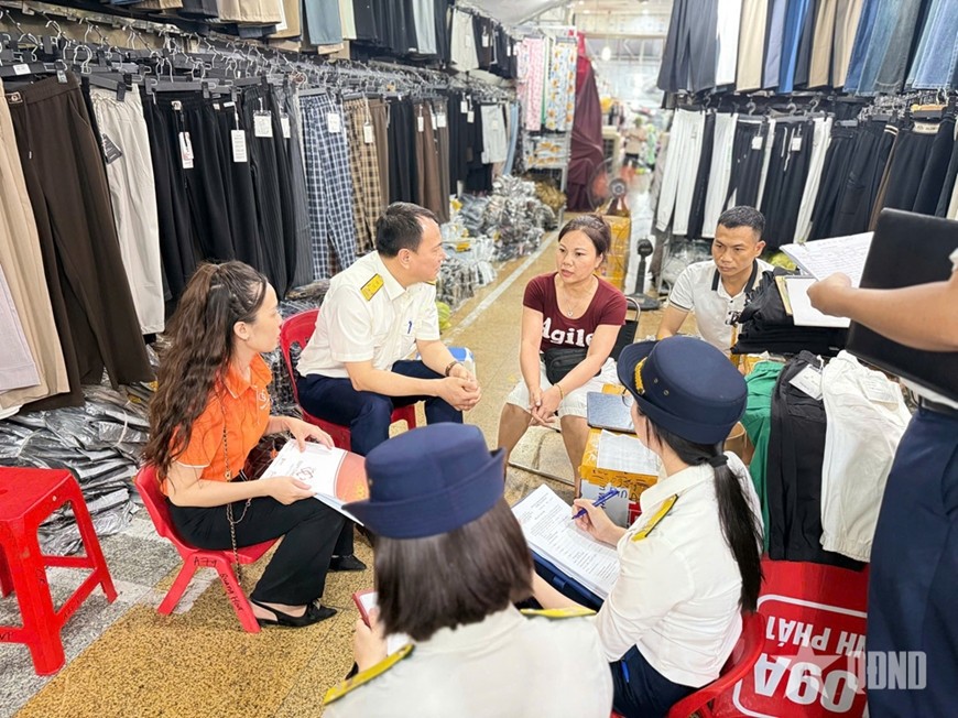 Cán bộ Chi cục Thuế Khu vực I hướng dẫn hộ kinh doanh triển khai hóa đơn điện tử từ máy tính tiền. Ảnh: HƯƠNG GIANG