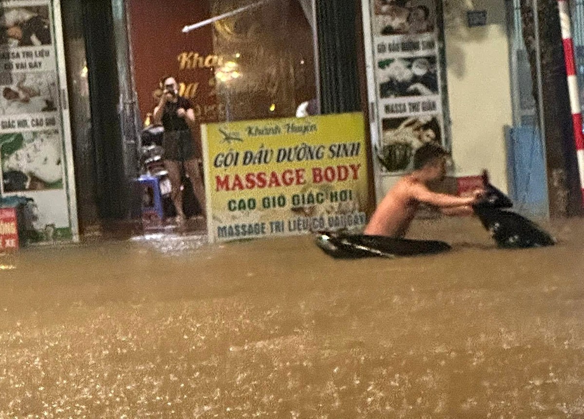 Người đàn ông đang cố gắng đẩy chiếc xe máy đi trong biển nước, dưới cơn mưa tầm tã. Theo chia sẻ của cư dân mạng, không ít phương tiện bị rơi biển số xe khi cố gắng đi trong điều kiện như này. (Ảnh: Otofun Thái Nguyên)