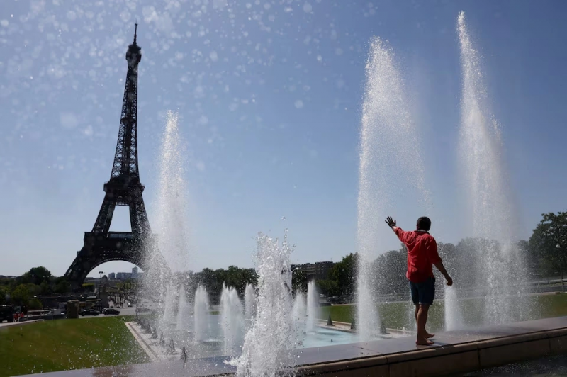 Một du khách giải nhiệt tại đài phun nước Trocadero bên cạnh tháp Eiffel khi đợt nắng nóng đầu hè tràn qua Paris, Pháp, ngày 1/7. Ảnh: Reuters