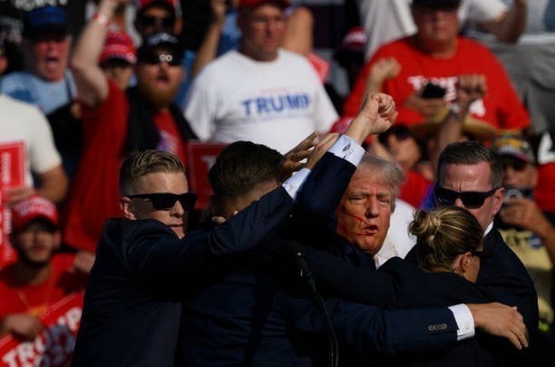 Ông Donald Trump được mật vụ Mỹ hộ tống rời khỏi bục diễn thuyết trong cuộc vận động tranh cử ở thành phố Butler, bang Pennsylvania sau khi xảy ra vụ nổ súng, ngày 13/7/2024. (Ảnh: Getty Images/TTXVN)