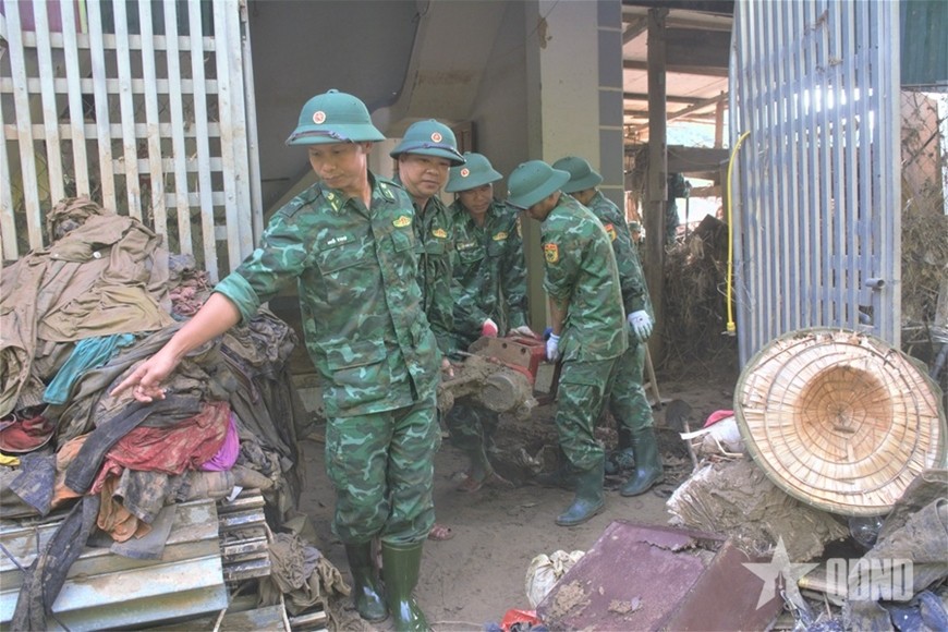 Cán bộ, chiến sĩ Đồn Biên phòng Cửa khẩu quốc tế Nậm Cắn giúp người dân tìm lại vật dụng từ đống bùn đất.