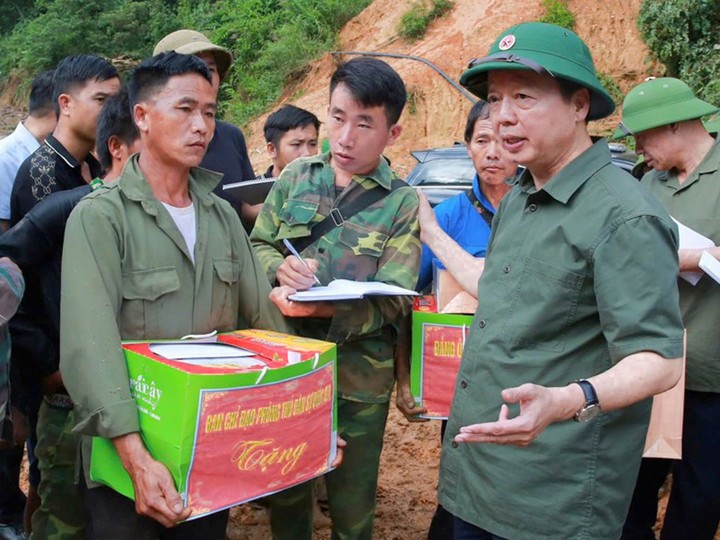 Trưởng bản Mùa A Thi (người cầm sổ tay) đang hỗ trợ các lực lượng cứu hộ, cứu nạn báo cáo Phó Thủ tướng Trần Hồng Hà công tác khắc phục hậu quả tại bản Háng Pu Xi. (Ảnh: VGP/Minh Khôi)