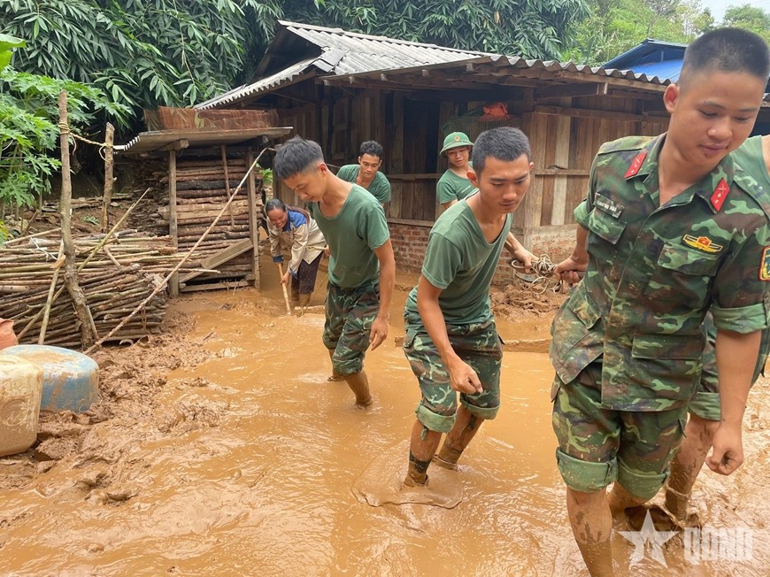 Cán bộ, chiến sĩ giúp người dân san gạt bùn đất, vệ sinh nhà cửa.