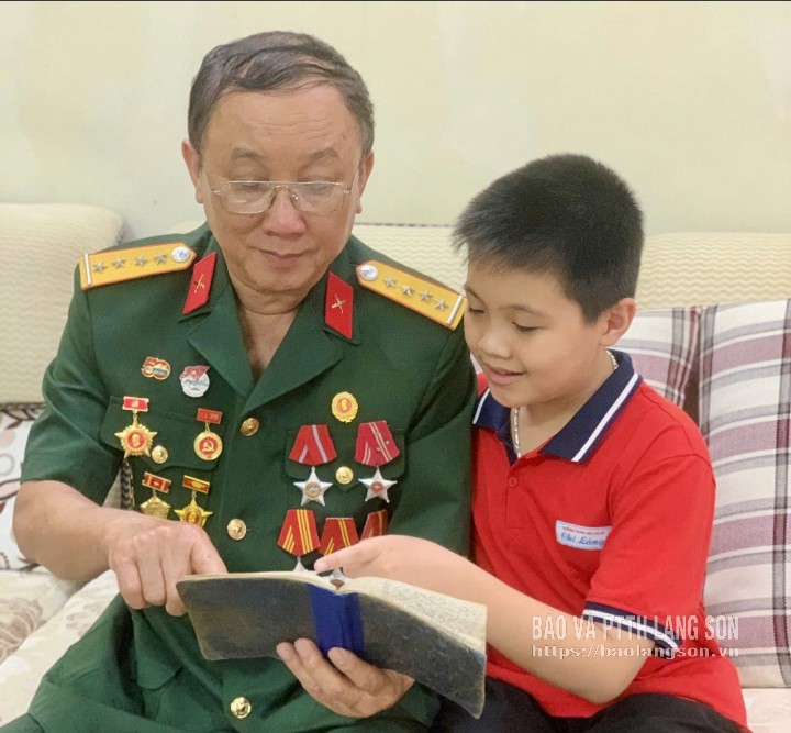 Cựu chiến binh Nguyễn Đức Lập, phường Lương Văn Tri kể lại kỷ niệm thời kháng chiến cho cháu nội nghe